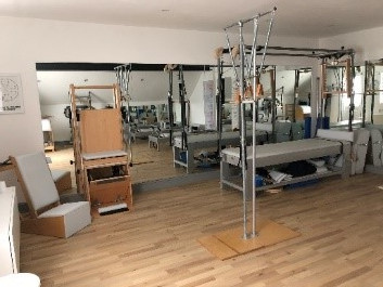 The studio: a wooden floor with reformers, a trapeze table, a chair and mirrors